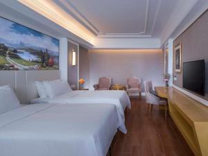 a hotel room with two beds and a flat screen tv at Vienna Hotel Shenzhen Pingdi Huancheng South Road in Longgang