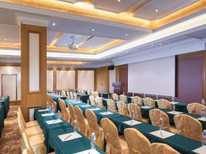 une salle de conférence avec des tables, des chaises et un écran dans l'établissement Vienna Hotel Shenzhen Pingdi Huancheng South Road, à Longgang