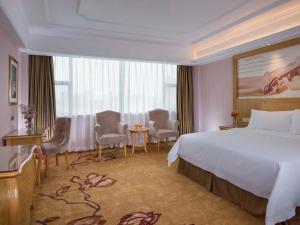 a hotel room with a bed and a table and chairs at Vienna Hotel Shenzhen Pingdi Huancheng South Road in Longgang