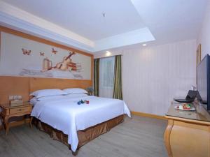 Pokój hotelowy z dużym łóżkiem i telewizorem w obiekcie Vienna Hotel Shandong Laizhou Langhu International Plaza w mieście Laizhou