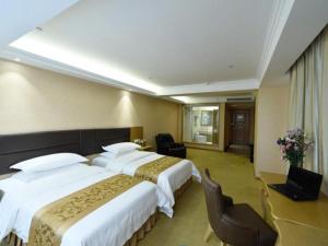 a hotel room with two beds and a desk at Vienna Hotel Shandong Yantai Wanda Plaza Suochengli in Yantai