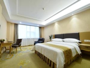 um quarto de hotel com uma cama grande e uma janela em Vienna Hotel Shandong Yantai Wanda Plaza Suochengli em Yantai