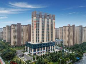 a large tall building in the middle of a city at Vienna Hotel Shandong Liaocheng High-Tech Zong Yueji Park in Liaocheng