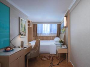 a hotel room with a bed and a desk with a computer at Vienna Hotel Shandong Liaocheng High-Tech Zong Yueji Park in Liaocheng