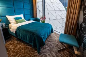 a bedroom with a blue bed and a chair at Sono Hotel in Brno