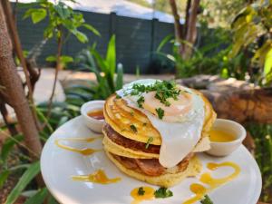 una pila di pancake su un piatto bianco con salsa per immersione di Livingstone Lodge a Victoria Falls