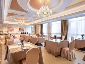 un restaurant avec des tables et des chaises et un lustre dans l'établissement Vienna Hotel Zhejiang Jinhua Jinyuhuayuan, à Chengnan