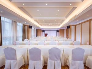 una sala de conferencias con una mesa grande con sillas blancas en Vienna Hotel Zhejiang Jinhua Jinyuhuayuan, en Chengnan