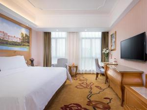 a hotel room with a bed and a flat screen tv at Vienna Hotel Zhejiang Jinhua Jinyuhuayuan in Chengnan