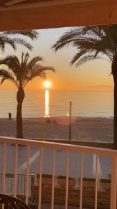 サロウにあるbello-horizonte Salou playaのヤシの木が茂る海岸の夕日