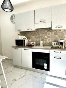 a kitchen with white cabinets and a microwave at L’Angolo Degli Dei in Agrigento