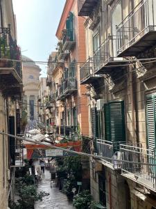a narrow street with buildings and people walking down it at Le Colonne del Massimo Apartment in Palermo