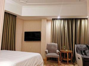Vienna Hotel Chongqing Wanzhou Wanda Plaza في Wanxian: غرفة فندقية فيها سرير وكرسي وتلفزيون