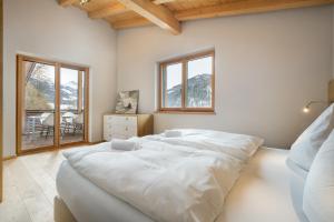 a bedroom with a large white bed and windows at Ski & Golf Auszeit Apartment by Alpine Host Helpers in Kitzbühel