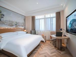 a bedroom with a large white bed and a flat screen tv at Vienna Hotel Wuhu Ruifeng Shangbo City in Wuhu