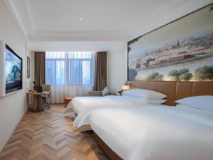 a hotel room with two beds and a painting on the wall at Vienna Hotel Wuhu Ruifeng Shangbo City in Wuhu