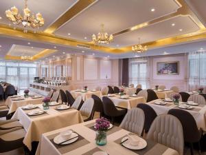 a dining room with tables and chairs and chandeliers at Vienna Hotel Xuzhou Junsheng Plaza Benteng Avenue Metro Station in Xuzhou