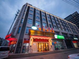 a large building on a city street with signs on it at Vienna Hotel Xuzhou Junsheng Plaza Benteng Avenue Metro Station in Xuzhou