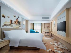 - une chambre avec un grand lit blanc et une télévision à écran plat dans l'établissement Vienna Hotel Fuzhou Changle Shouzhan Hangcheng Metro Station, à Changle