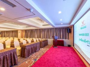 a conference room with tables and chairs and a screen at Venus International Hotel Guangdong Huizhou West Lake in Huizhou