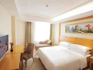 Habitación de hotel con cama blanca grande y escritorio. en Vienna Hotel Shenyang Central Street en Shenyang