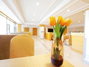 un jarrón lleno de tulipanes amarillos sentados en una mesa en Vienna Hotel Shenyang Central Street en Shenyang