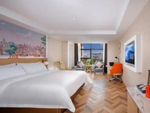 a bedroom with a large white bed and a desk at Vienna Hotel Guiyang Yunyan District Government in Guiyang