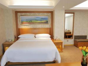 ein Schlafzimmer mit einem großen weißen Bett in einem Zimmer in der Unterkunft Vienna Hotel Shenyang Central Street in Shenyang