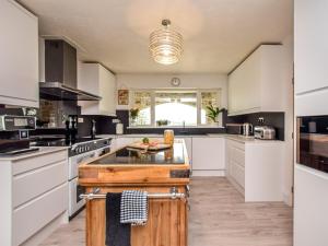 a large kitchen with white cabinets and a large island at 6 Bed in Buckland Brewer SWOLD in Buckland Brewer