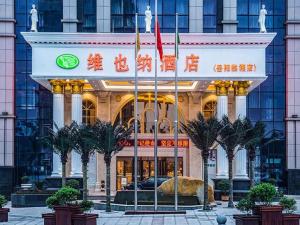 un bâtiment avec deux drapeaux devant lui dans l'établissement Vienna Hotel Hunan Yueyang Linxiang, à Linxiang