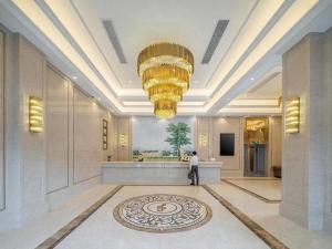 eine Person, die in einer Lobby mit einem großen Kronleuchter steht in der Unterkunft Vienna Hotel Fuzhou Mawei in Mawei