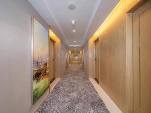 einen Flur mit einem langen Gang mit Gemälden an den Wänden in der Unterkunft Vienna Hotel Fuzhou Mawei in Mawei
