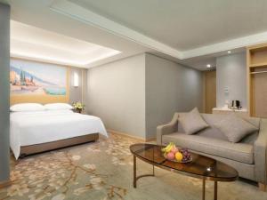 een slaapkamer met een bed, een bank en een tafel bij Vienna Hotel Guangxi Hechi Jinchengjiang Baima Street in Hechi