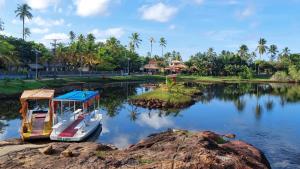 a boat is docked on a river with palm trees at Vilage Aconchegante - Imbassaí in Imbassai