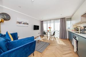 Farringdon Serviced Apartments في لندن: غرفة معيشة مع أريكة زرقاء ومطبخ