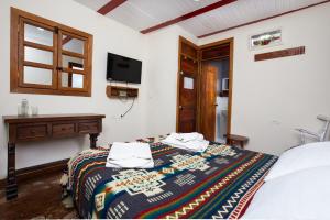 a bedroom with a bed and a tv on the wall at IntiLuna Hostel in Salento