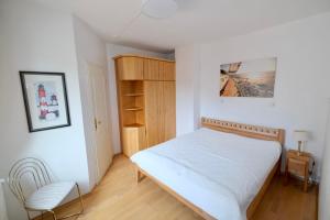 a bedroom with a white bed and a chair at Landjägerhaus am Südstrand - Wohnung 4 + 5 in Wyk auf Föhr