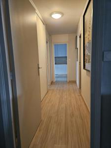 un pasillo con una puerta que conduce a una habitación con suelo de madera en Chambre d'hôte - hypercentre, en Annemasse