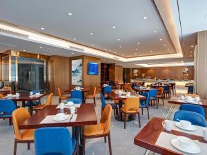 un restaurante con mesas de madera y sillas azules en Venus Royal Hotel Guangxi Wuzhou Sanqicheng Meiguihu Park, en Wuzhou