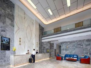 a lobby with two people standing at a reception desk at Venus Royal Hotel Guangxi Wuzhou Sanqicheng Meiguihu Park in Wuzhou