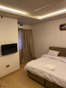 a bedroom with a bed and a flat screen tv at JF Royal Hotel & Suites in Ogbomoso