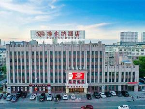a large building with cars parked in a parking lot at Vienna Hotel Heilongjiang Qiqihar South Road in Qiqihar