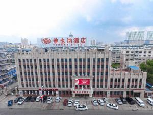 ein großes Gebäude mit Autos auf einem Parkplatz in der Unterkunft Vienna Hotel Heilongjiang Qiqihar South Road in Qiqihar