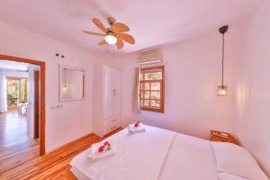 a white bedroom with a bed and a ceiling fan at Yoga House Kaş in Kaş