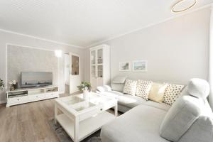 Il comprend un salon blanc doté d'un canapé et d'une télévision. dans l'établissement Strandfee Wohnung 21, à Grömitz