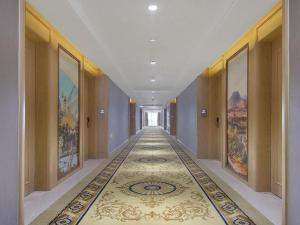 einen Flur mit Teppichboden in einem Gebäude mit Gemälden in der Unterkunft Vienna Hotel Anhui Lujiang International Building Materials Market Wuzhong in Lujiang