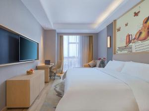 ein Hotelzimmer mit einem großen Bett und einem Flachbild-TV in der Unterkunft Vienna Hotel Anhui Lujiang International Building Materials Market Wuzhong in Lujiang