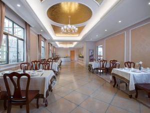 a dining room with tables and chairs and a chandelier at Vienna Hotel Guangdong Foshan Wenhua North Road in Nanhai