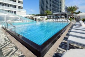 einem großen Pool mit weißen Stühlen und einem Gebäude in der Unterkunft SuitesRUs At W Hotel Fort Lauderdale in Fort Lauderdale
