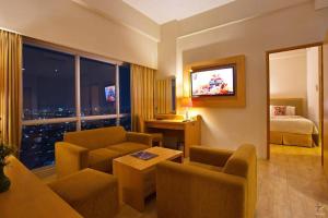 a hotel room with a bed and a living room at Horison Ultima Semarang in Jomblang